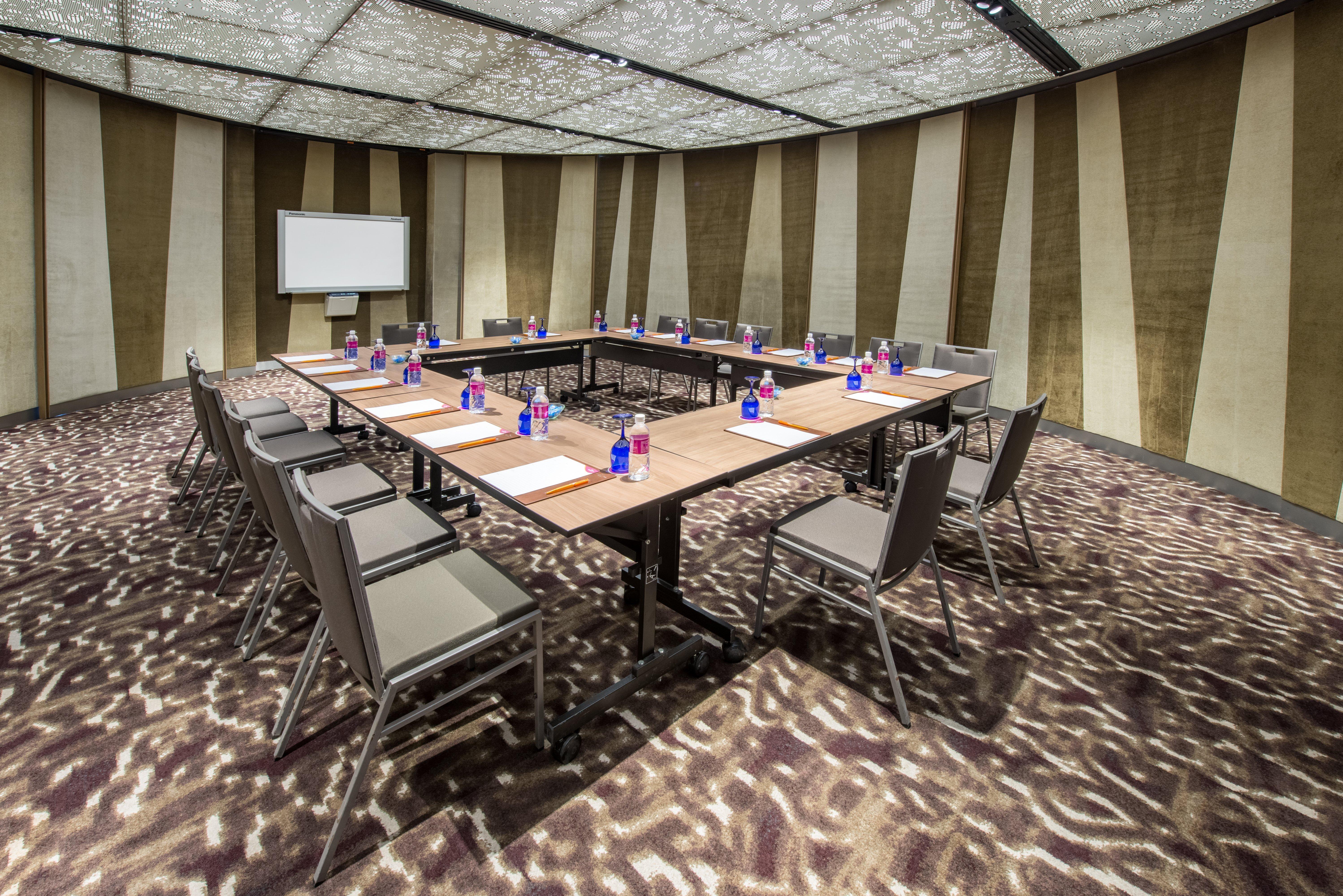 Crowne Plaza Changi Airport By Ihg Σιγκαπούρη Εξωτερικό φωτογραφία The photo depicts a conference room set up for a meeting. There is a large rectangular table in the center with chairs arranged around it. Each seating area has a small bottle of water and a notepad, suggesting it's prepared for attendees. The room f