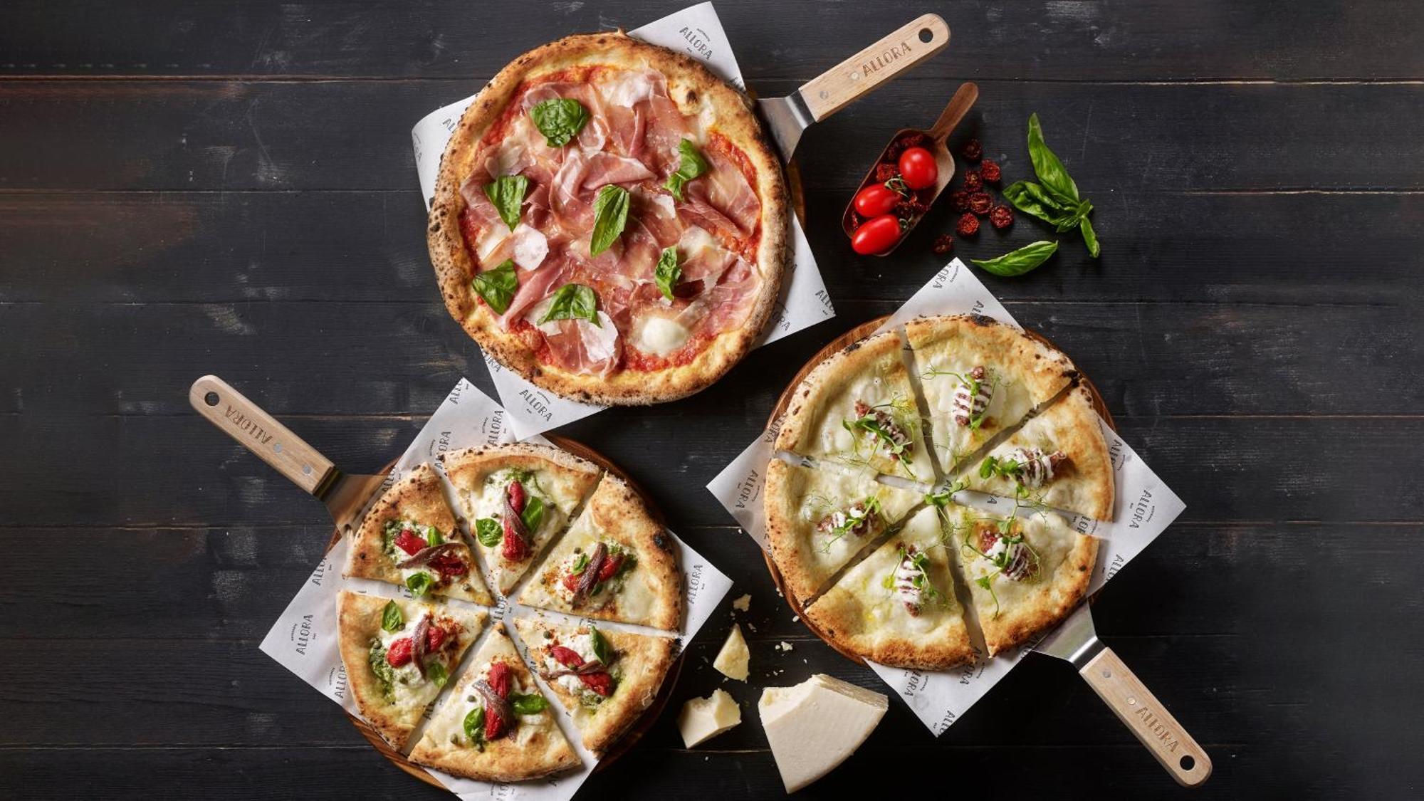 Crowne Plaza Changi Airport By Ihg Σιγκαπούρη Εξωτερικό φωτογραφία The photo depicts three different types of pizzas on wooden serving paddles. 

1. **Top Pizza**: This pizza features a combination of thinly sliced cured meats, likely prosciutto, alongside fresh basil leaves and mozzarella cheese on a light-colored 