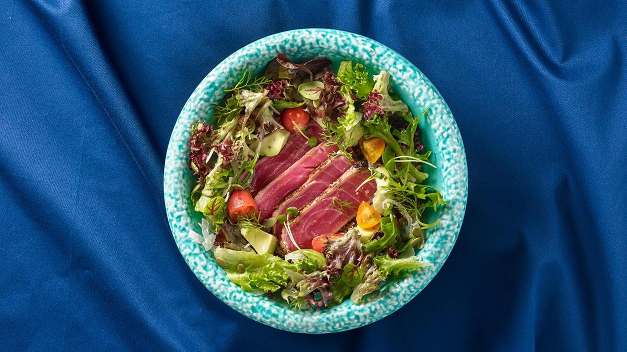 Crowne Plaza Changi Airport By Ihg Σιγκαπούρη Εξωτερικό φωτογραφία The photo shows a bowl of salad featuring a variety of fresh leafy greens, including different types of lettuce. There are sliced pieces of seared tuna placed over the salad, adding a protein element. The salad is garnished with cherry tomatoes and p