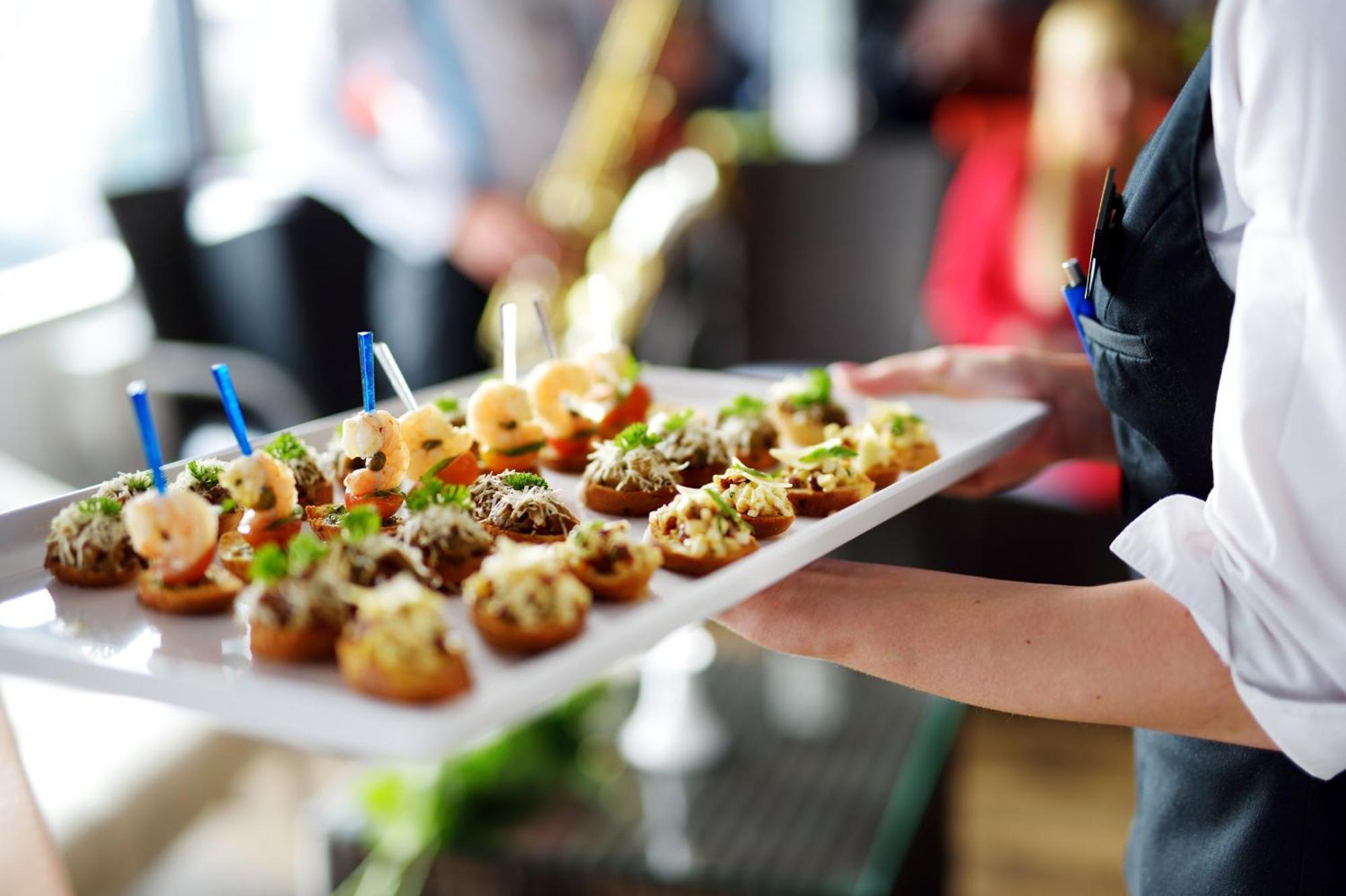 Crowne Plaza Changi Airport By Ihg Σιγκαπούρη Εξωτερικό φωτογραφία The photo shows a tray of appetizers being held by a waiter. The tray is filled with various small bites that appear to be decorative and gourmet. Some of the appetizers feature toppings such as shrimp and what looks like a mix of herbs or spreads. T
